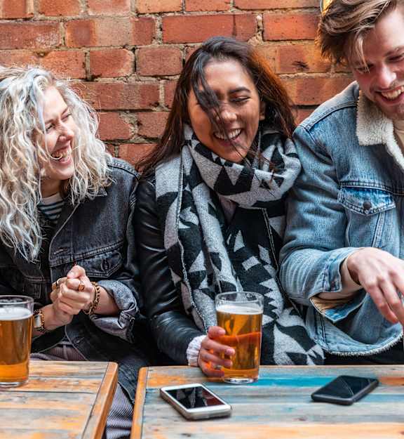Four people are sitting at a table with beer glasses in front of them.