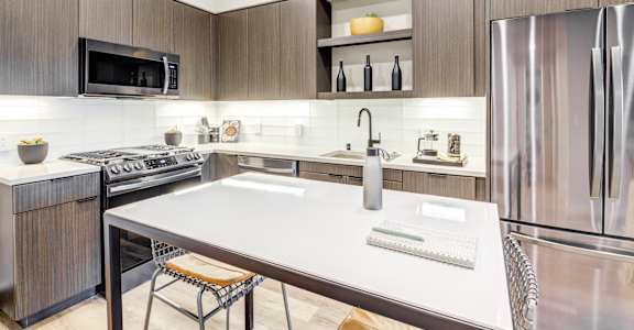 A modern kitchen with a stainless steel refrigerator and a white island counter.
