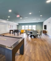 oa game room with a pool table, shuffle board, and chairs at the vue apartments in indianapolis 