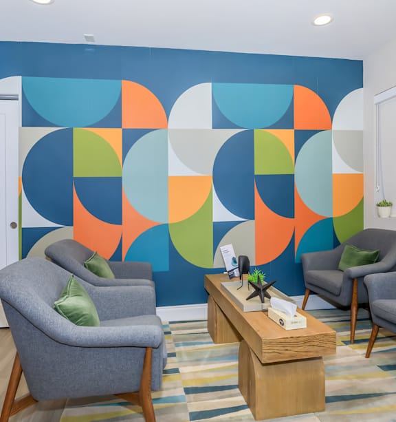 A room with a blue wall and three grey chairs.