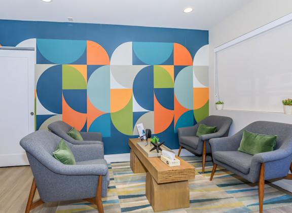 A room with a blue wall and three grey chairs.
