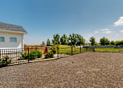 Thumbnail 3 of 4 - A house with a black fence and a gravel driveway.