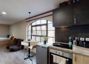 Thumbnail 7 of 8 - a kitchen and living room with a bed and a desk in a small apartment