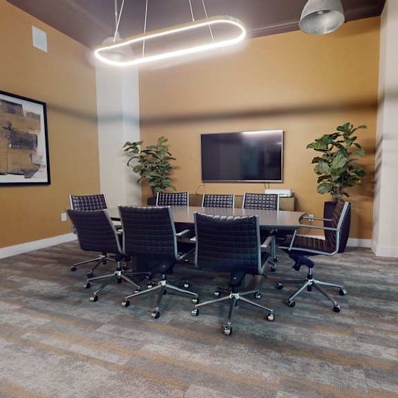 The conference room with a large conference table surrounded by chairs, artwork on the walls, and a TV at Loft at Watters Creek.  
