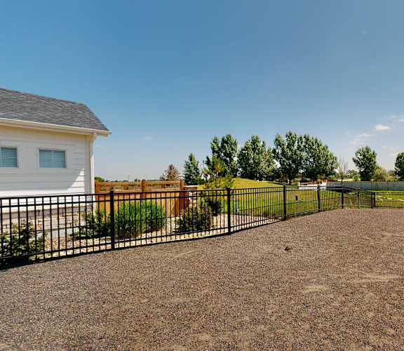 A house with a black fence and a gravel driveway.