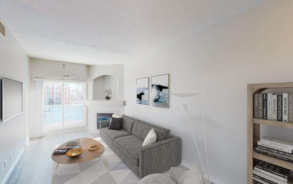 A living room with a grey couch, a coffee table, and a bookshelf.