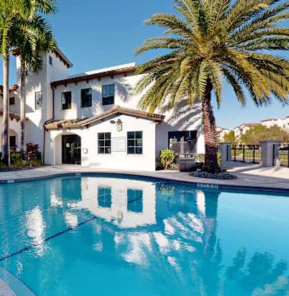 A large white house with a pool in front of it.