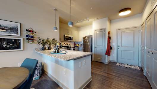 a kitchen with a large island and a stainless steel refrigerator at The Address Galleria, Matthews, NC, 28105