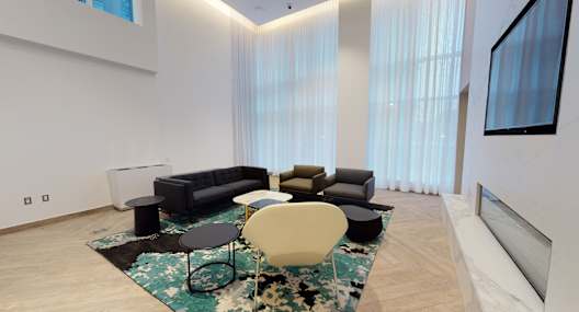 A living room with a black couch, a white chair, and a rug.