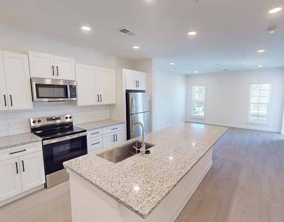 A kitchen with white cabinets and a granite countertop.