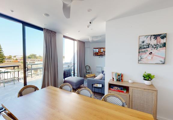 a living room with a wooden table and chairs and a balcony