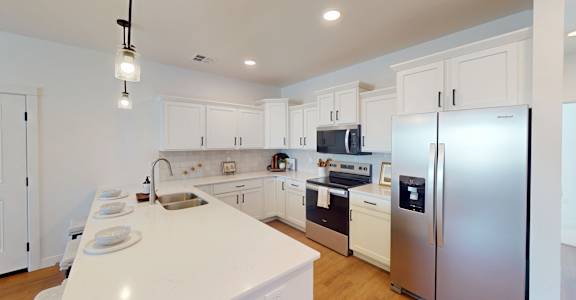 A modern kitchen with white cabinets and appliances.