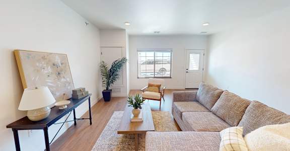 A living room with a brown couch and a painting on the wall.
