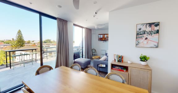 a living room with a wooden table and chairs and a balcony