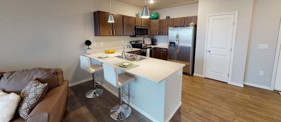 a kitchen with a bar and a living room with a couch at Upscale Living at the Grand off 45th, Fargo, 58104