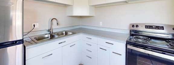A kitchen with white cabinets and a stainless steel refrigerator.