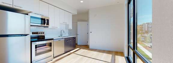 A modern kitchen with wooden floors and stainless steel appliances.