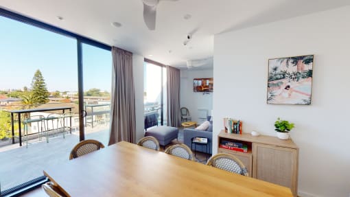 a living room with a wooden table and chairs and a balcony