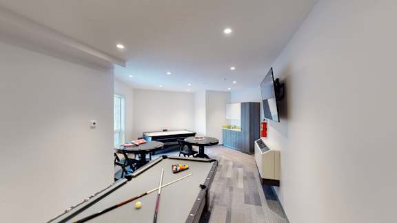 A room with a pool table and a television mounted on the wall.