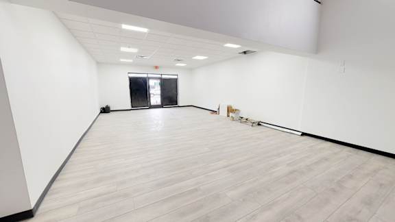 A large empty room with wooden flooring and white walls.