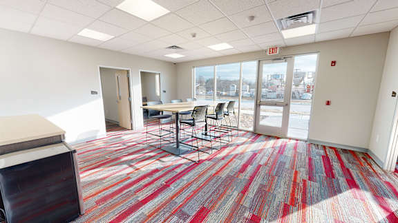A room with a striped carpet and a table with chairs.
