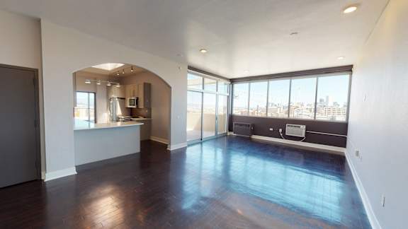 A large empty room with a window overlooking a cityscape.