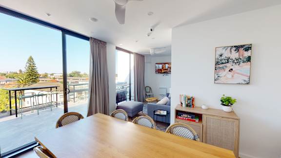 a living room with a wooden table and chairs and a balcony