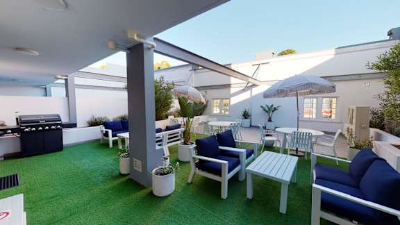 a rendering of a patio with blue furniture and a grill