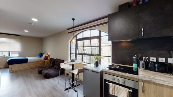 a kitchen and living room with a bed and a desk in a small apartment