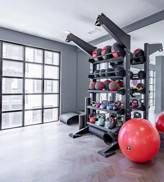 Spacious free-weight area with kettlebells, exercise balls, and floor mats at Novel Cary