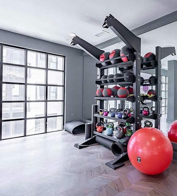 Spacious free-weight area with kettlebells, exercise balls, and floor mats at Novel Cary