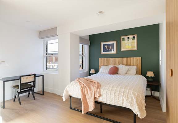 A bedroom with a bed, desk, and chair.