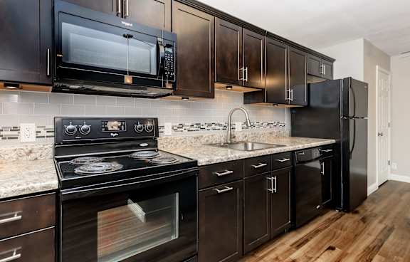 A black stove and microwave in a kitchen with dark wood cabinets.