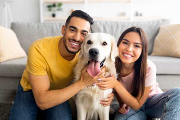 A man and woman are sitting on a couch with a white dog.