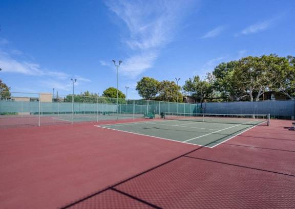 a tennis court with red and green court surfaces and a fence