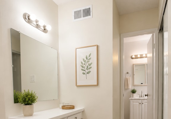 A bathroom with a white vanity and a mirror above it.