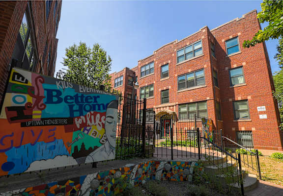A brick building with a mural on the fence in front.