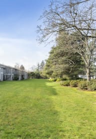 a row of condominiums with a green lawn and trees
