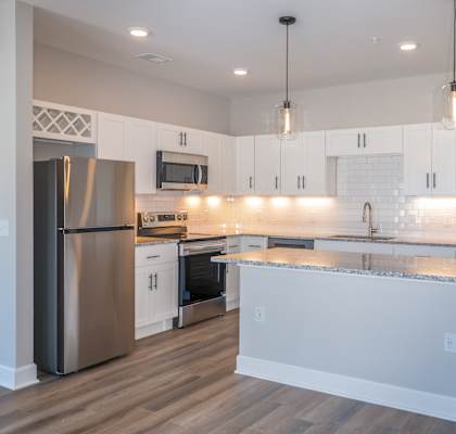 A modern kitchen with a granite countertop and stainless steel appliances.