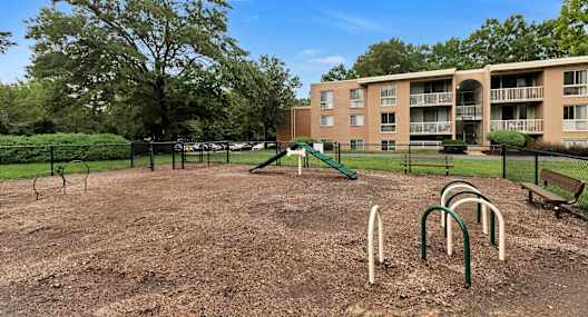 A playground with a green slide and a brown dirt ground.