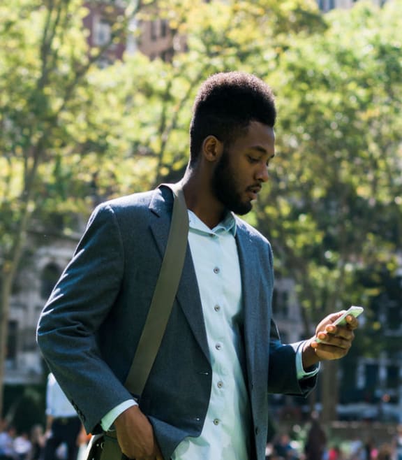 a man walking in a park looking at his phone at The Acadia at Metropolitan Park, Arlington, VA