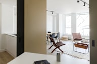 A modern living room with a white table and brown chairs.