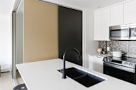 A modern kitchen with a white countertop and black appliances.