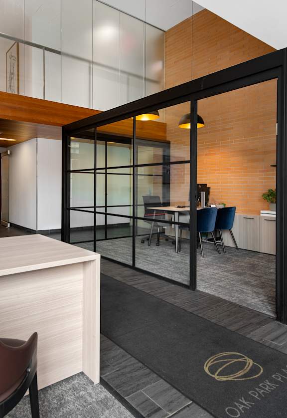 A modern office space with a brown leather chair and a wooden desk.