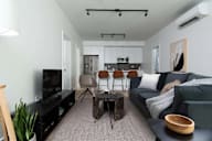 A living room with a black couch, a wooden table, and a television.