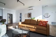 A living room with a brown couch and a glass table.