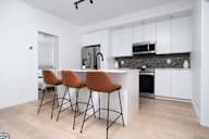 A kitchen with white cabinets and a black counter.