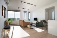 A living room with a sofa set, a chair, and a television.