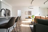 A modern kitchen with a bar area and a living room area.