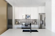 A modern kitchen with a stainless steel refrigerator and a black faucet.